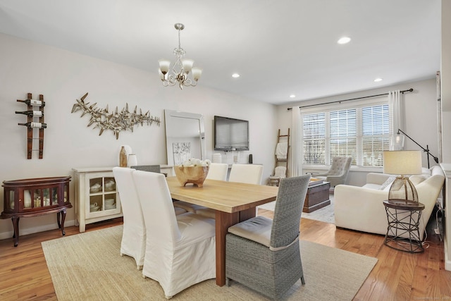 dining area with baseboards, light wood finished floors, recessed lighting, and an inviting chandelier