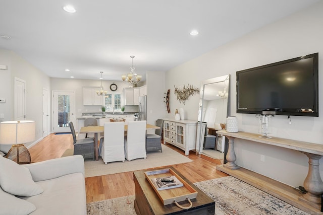 living area with light wood-type flooring, a notable chandelier, and recessed lighting