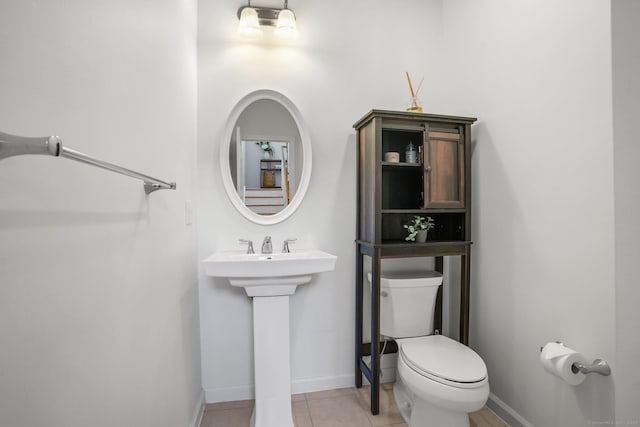 half bathroom with toilet, baseboards, and tile patterned floors