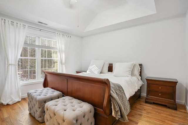 bedroom featuring light wood finished floors, baseboards, visible vents, ceiling fan, and vaulted ceiling