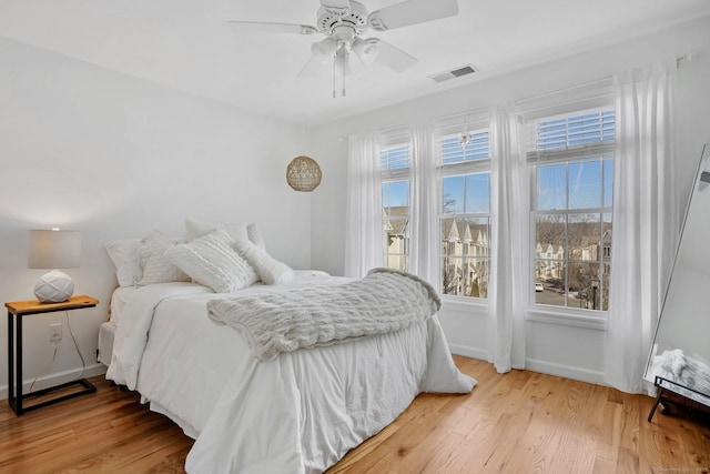 bedroom with baseboards, visible vents, ceiling fan, and light wood finished floors