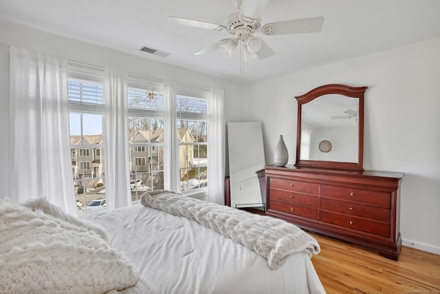 bedroom featuring visible vents, ceiling fan, light wood-style flooring, and multiple windows