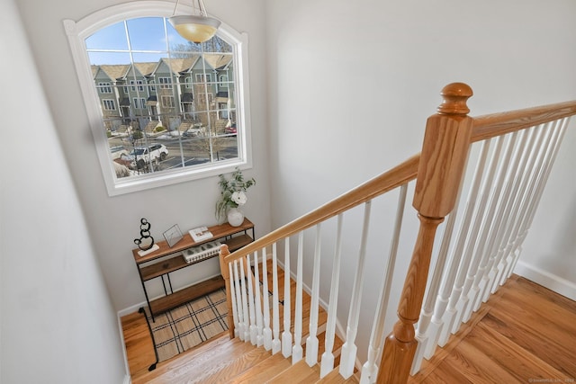 stairs featuring baseboards, a wealth of natural light, and wood finished floors