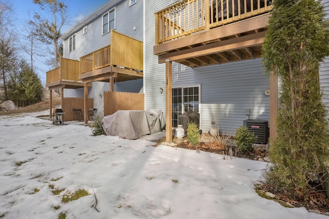 snow covered back of property with central AC unit and a patio area