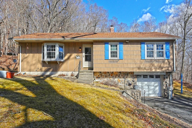 view of front of property with a chimney, entry steps, a front lawn, a garage, and aphalt driveway