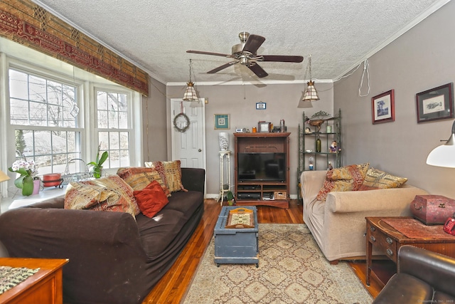 living area with ornamental molding, a textured ceiling, wood finished floors, baseboards, and ceiling fan