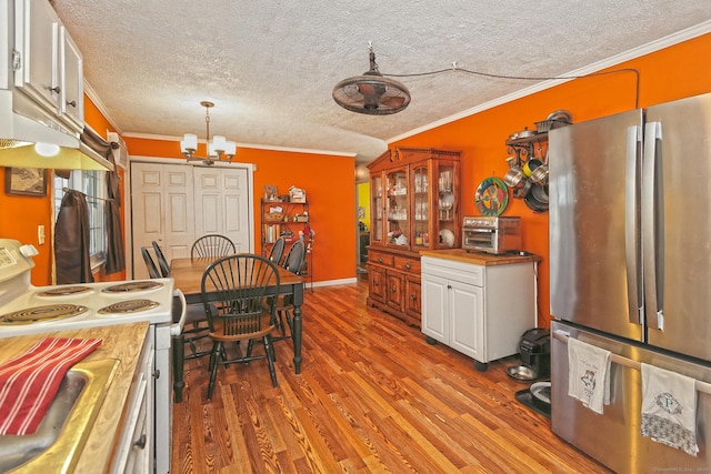 kitchen with wood finished floors, electric stove, crown molding, and freestanding refrigerator