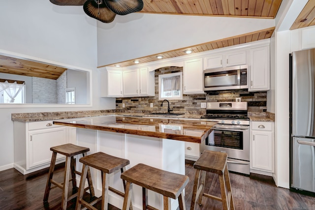 kitchen featuring white cabinetry, stainless steel appliances, lofted ceiling, and a sink