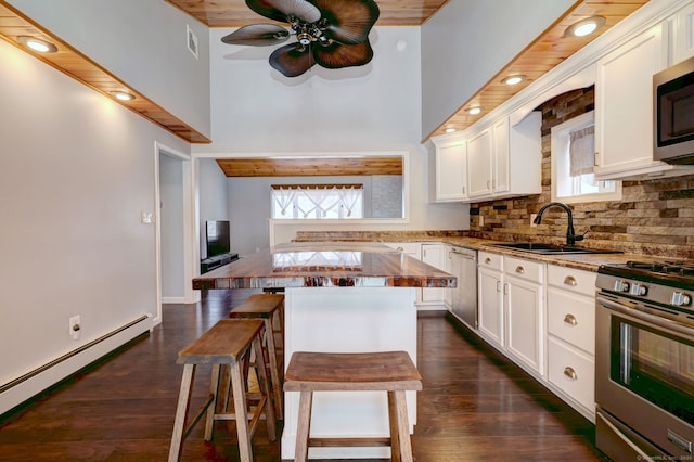 kitchen with visible vents, stainless steel appliances, white cabinets, decorative backsplash, and baseboard heating