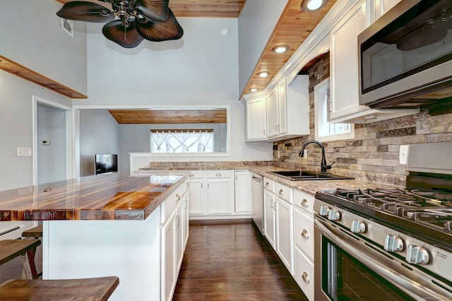 kitchen featuring a sink, stainless steel appliances, white cabinets, decorative backsplash, and wooden counters