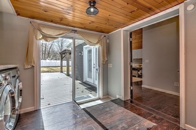 doorway to outside with baseboards, hardwood / wood-style flooring, wood ceiling, and washing machine and clothes dryer