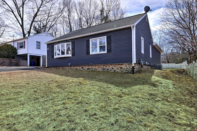 view of front of home featuring central air condition unit, a shingled roof, a front yard, and fence