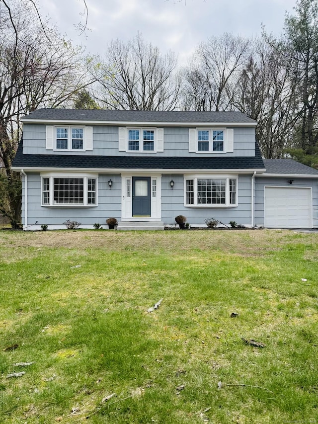 view of front of home featuring an attached garage, roof with shingles, and a front yard