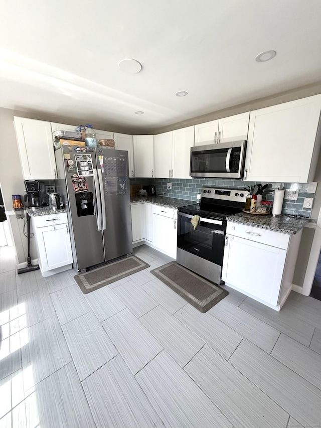 kitchen featuring backsplash, dark stone countertops, appliances with stainless steel finishes, and white cabinets