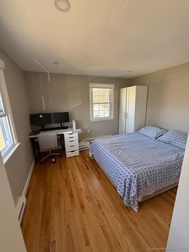 bedroom featuring light wood-style flooring, baseboards, and baseboard heating