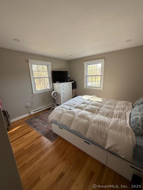 737 Burnham St, East Hartford, CT 06108 - bedroom featuring a baseboard radiator, wood finished floors, baseboards, and multiple windows