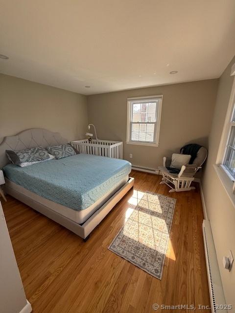 737 Burnham St, East Hartford, CT 06108 - bedroom featuring multiple windows, baseboard heating, and wood finished floors