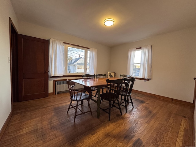 dining area featuring dark wood finished floors, radiator, and baseboards