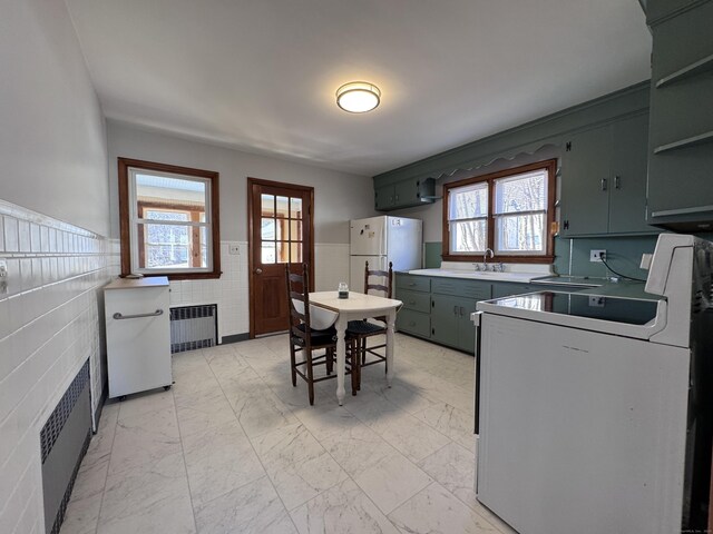 kitchen featuring marble finish floor, radiator, freestanding refrigerator, and a healthy amount of sunlight