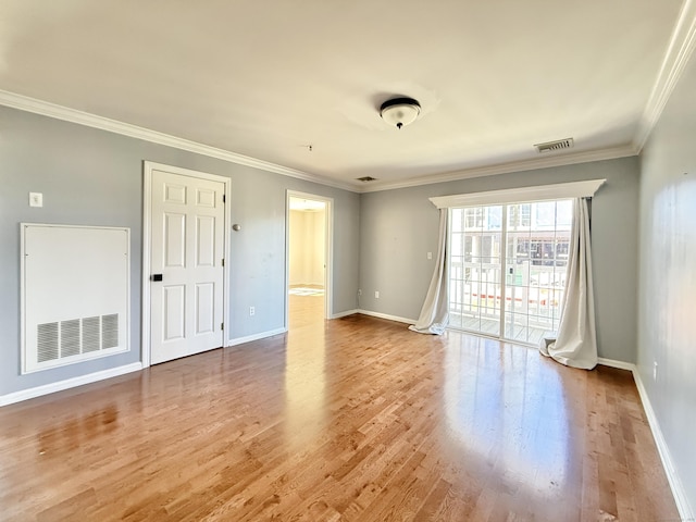 spare room with ornamental molding, wood finished floors, visible vents, and baseboards