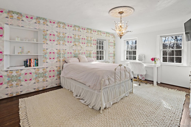 bedroom featuring a chandelier, wallpapered walls, and wood finished floors