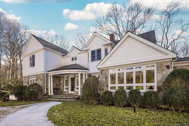 traditional home with stone siding and a chimney