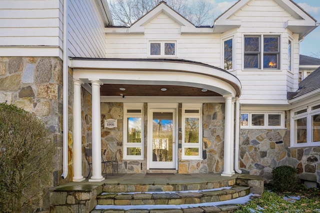 view of exterior entry with stone siding and covered porch