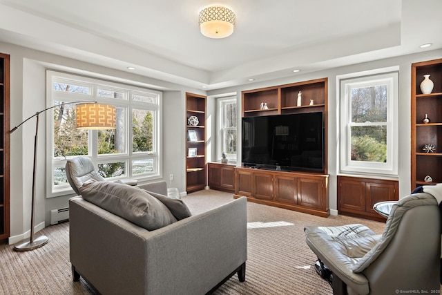 carpeted living room with a baseboard radiator, built in features, and baseboards