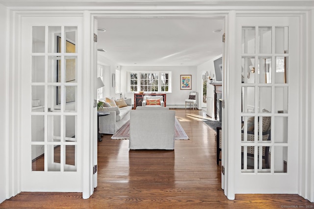 living room with a baseboard radiator, a fireplace, and wood finished floors