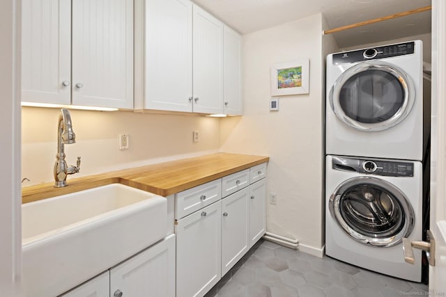 laundry room featuring a sink, stacked washer and clothes dryer, and baseboards