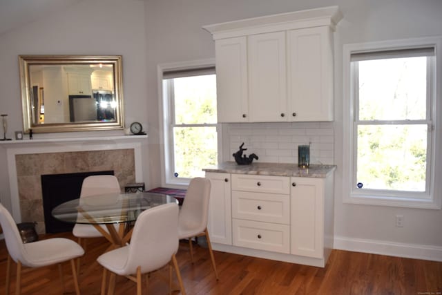 dining space featuring baseboards, a premium fireplace, and wood finished floors