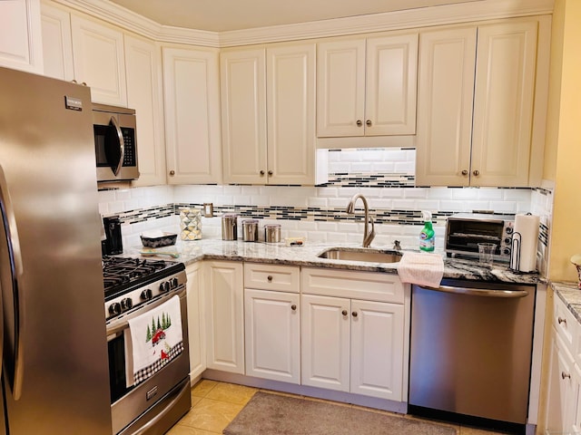 kitchen featuring light tile patterned floors, stainless steel appliances, a sink, decorative backsplash, and light stone countertops