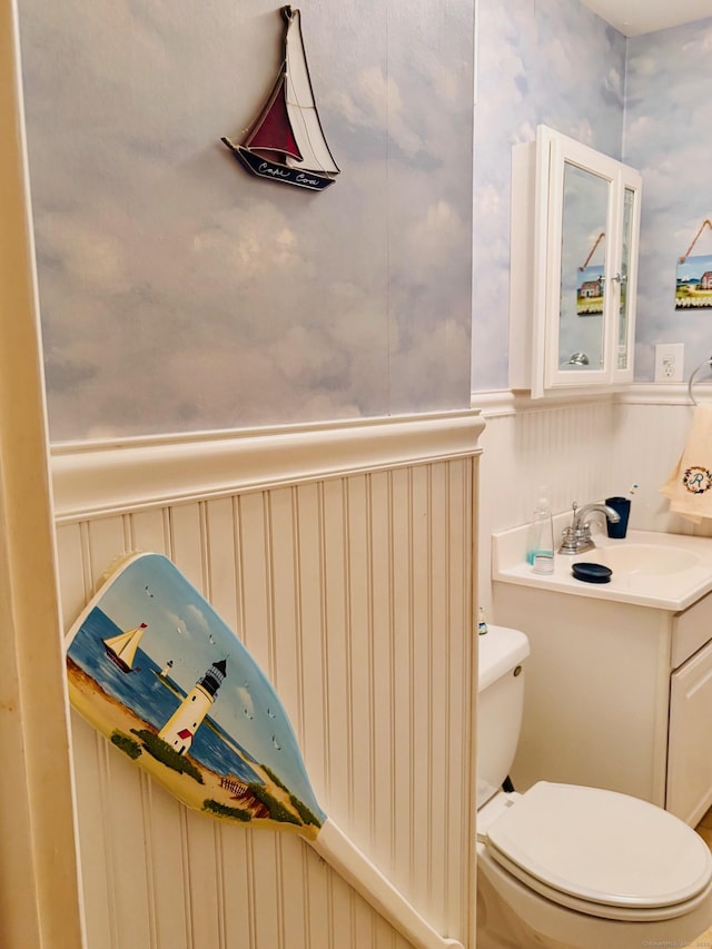 bathroom with wainscoting, vanity, and toilet