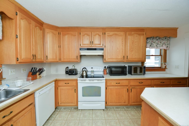 kitchen with light floors, light countertops, a sink, white appliances, and under cabinet range hood