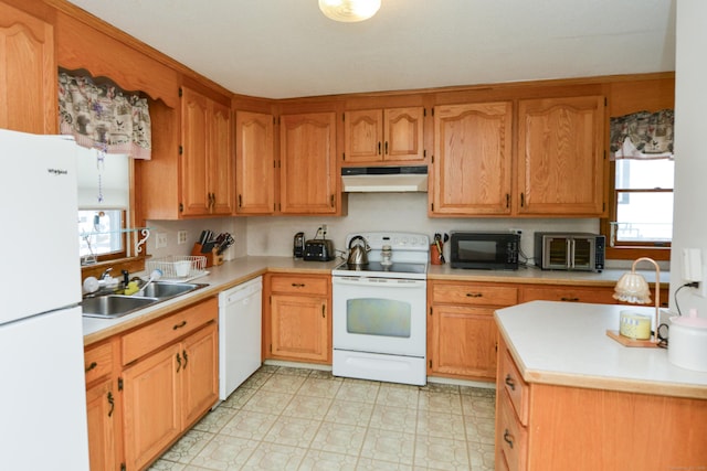 kitchen with light countertops, white appliances, a sink, and under cabinet range hood