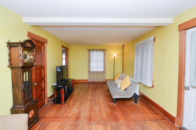 living area with beamed ceiling, baseboards, and wood finished floors