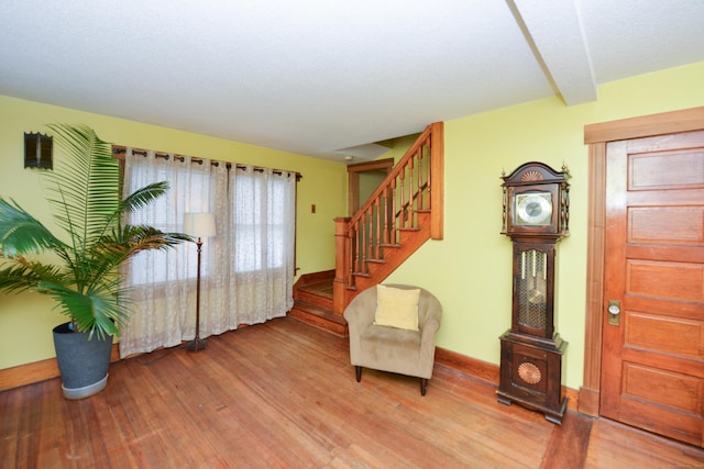 living area with stairs, wood finished floors, and baseboards