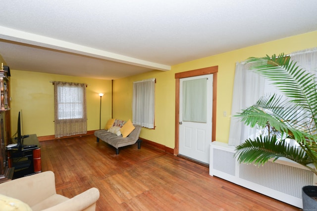 living area featuring baseboards, wood finished floors, and radiator