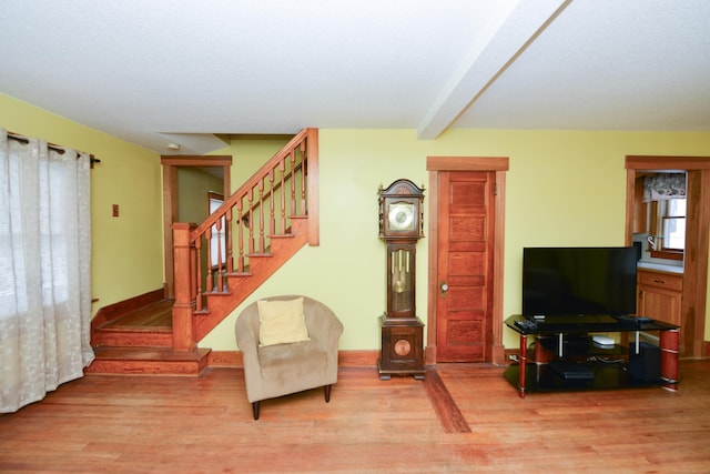 interior space with stairs, light wood finished floors, and beam ceiling