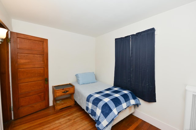 bedroom featuring radiator heating unit, baseboards, and wood finished floors