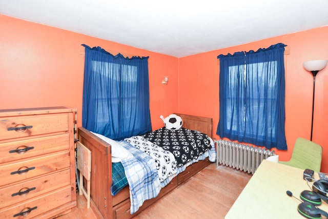 bedroom featuring radiator heating unit and wood finished floors