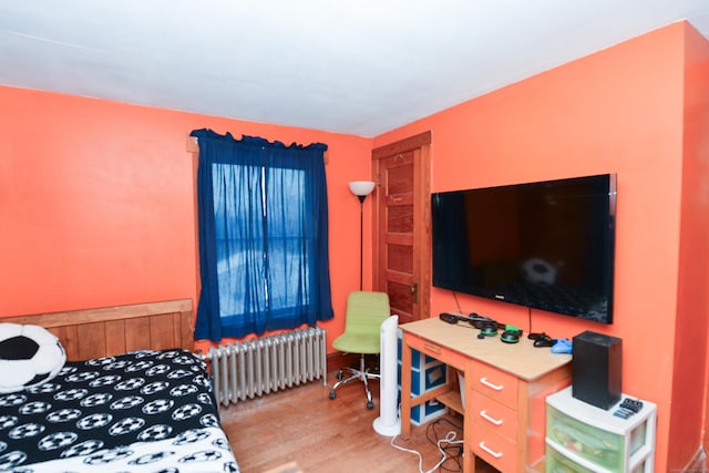 bedroom featuring wood finished floors and radiator