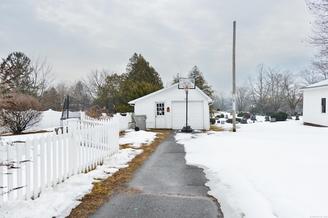 exterior space with aphalt driveway, an outbuilding, fence, and a detached garage