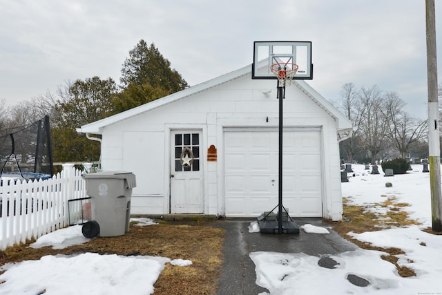 exterior space with a trampoline, fence, and a detached garage