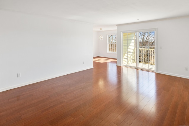 empty room featuring baseboards and dark wood-type flooring