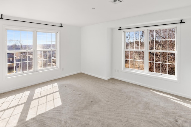 spare room featuring carpet flooring, visible vents, and baseboards