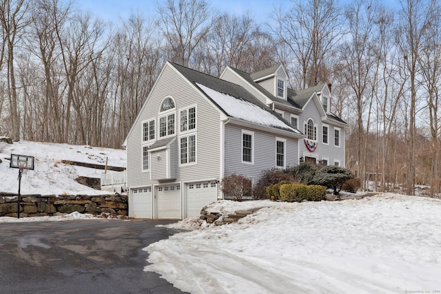 snow covered property featuring an attached garage and aphalt driveway