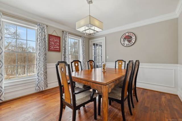 dining space featuring a wainscoted wall, wood finished floors, and crown molding