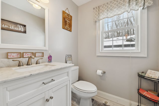 half bathroom with toilet, baseboards, and vanity