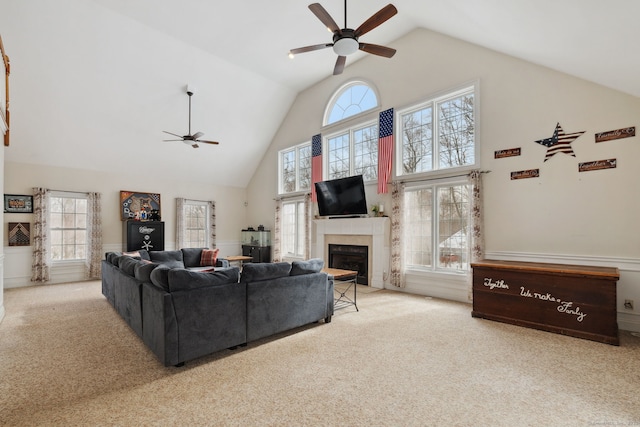 carpeted living area with a ceiling fan, a fireplace, and high vaulted ceiling